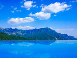 Green mountains and white clouds reflecting on a still blue pool